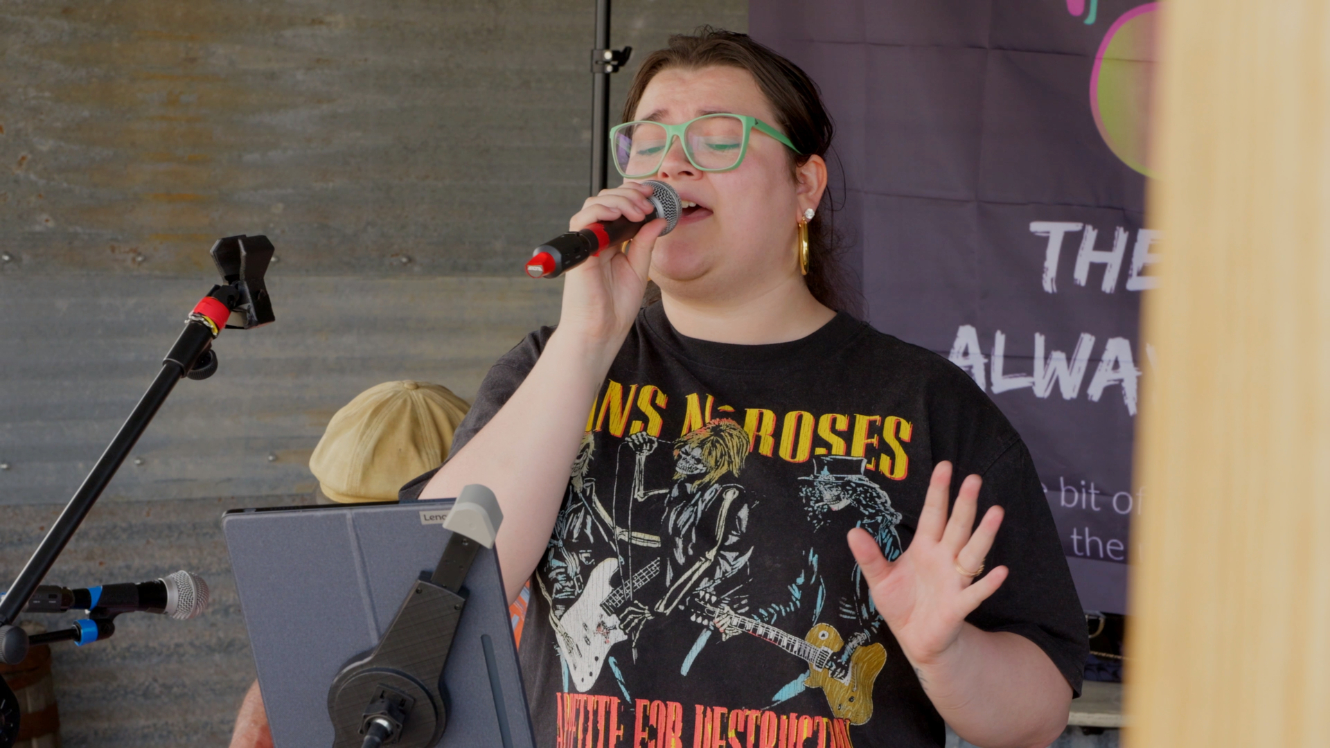 Singer mid-song in green glasses and a Guns N' Roses tee at the Chubby's stage