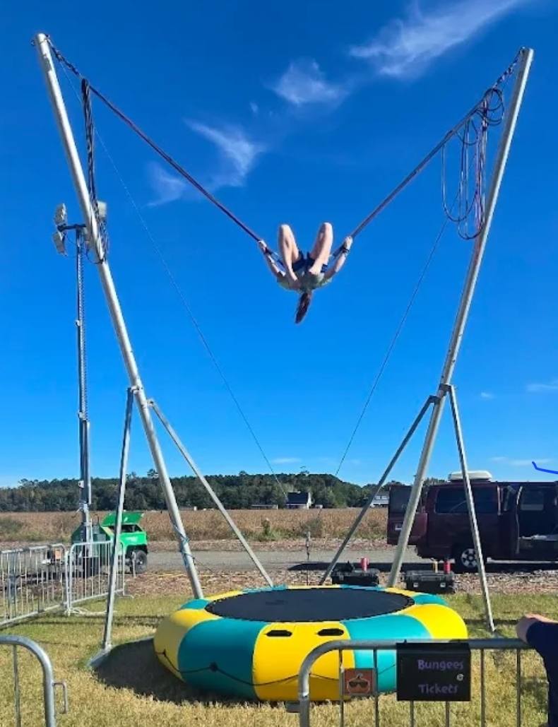 Kid soaring high on the bungee trampoline under a blue sky