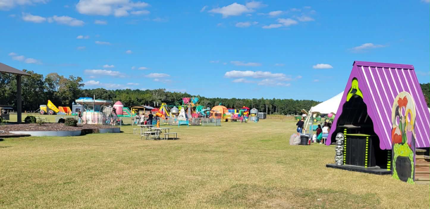 Wide view of the Chubby's midway with rides, bounce houses, and a witch hut
