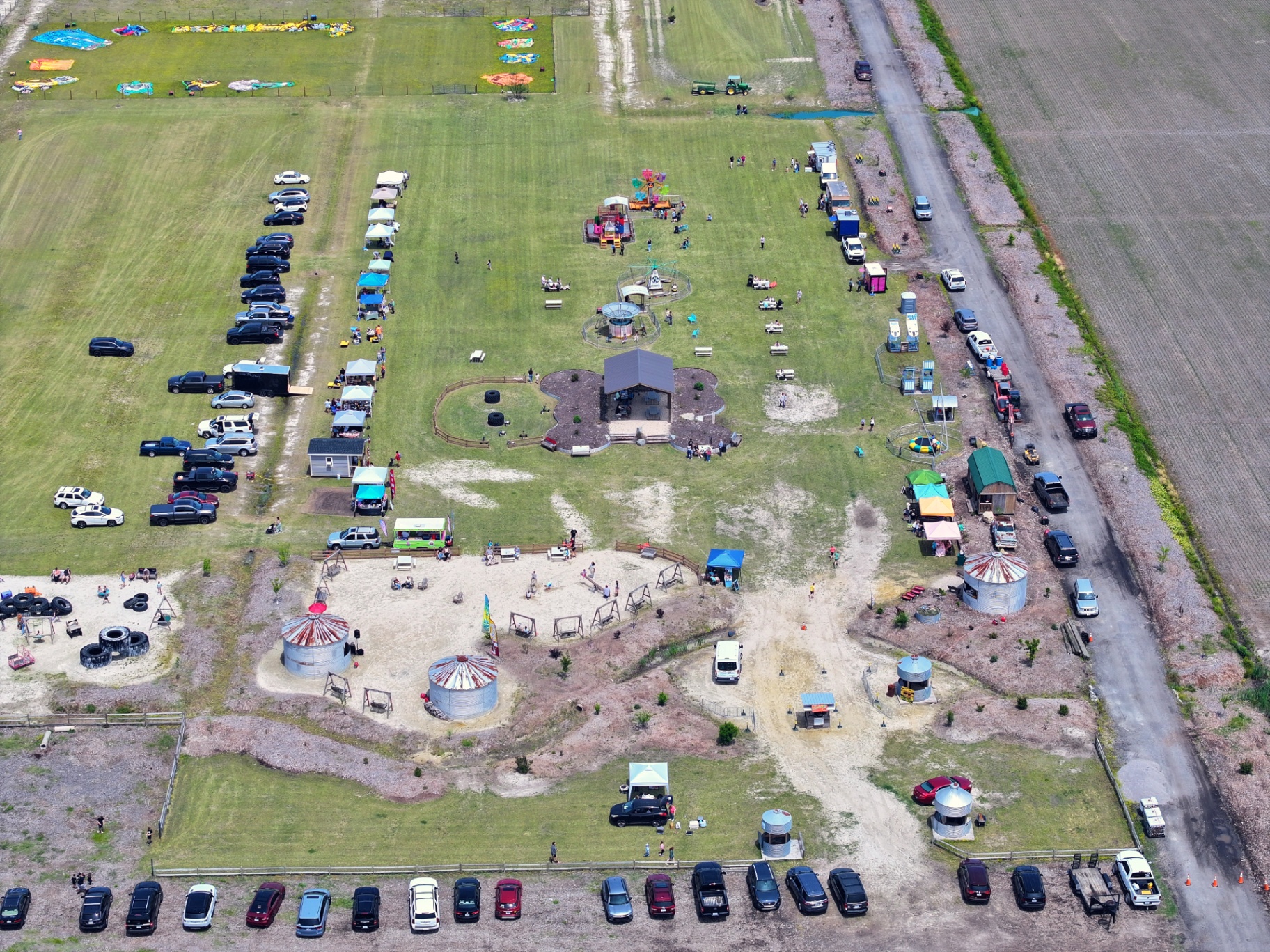 Aerial view of Chubby's Farm showing rides, vendor tents, sand play area, grain-bin structures, and parking